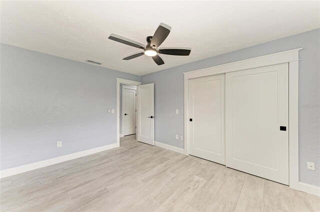 unfurnished bedroom with light wood-style flooring, a ceiling fan, baseboards, visible vents, and a closet