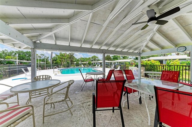 view of patio / terrace featuring a community pool, ceiling fan, fence, and outdoor dining space
