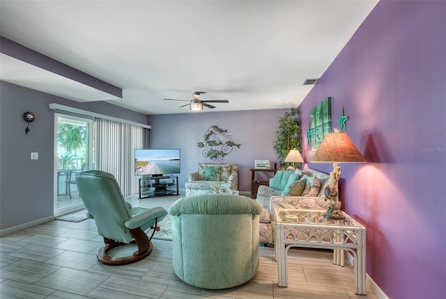 living area featuring visible vents, baseboards, and ceiling fan