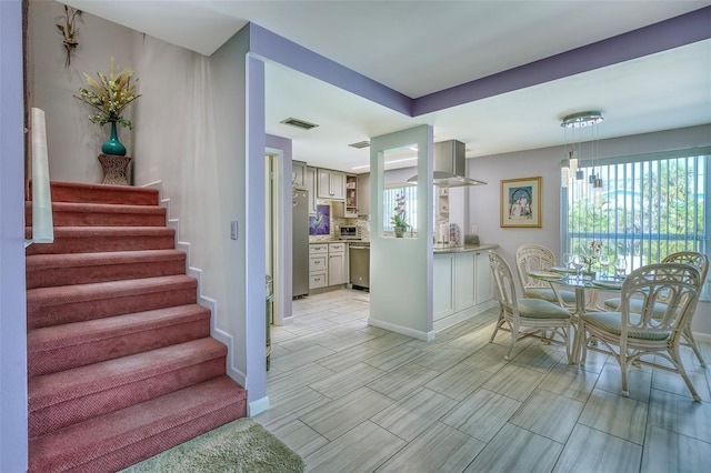 dining space featuring stairs, visible vents, and a healthy amount of sunlight