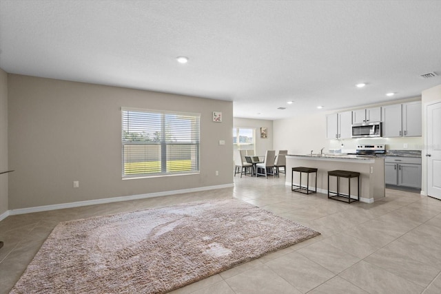 6314 Distant Haze Pl, Palmetto, FL 34221 - kitchen featuring appliances with stainless steel finishes, light tile patterned flooring, a kitchen island with sink, a breakfast bar area, and recessed lighting