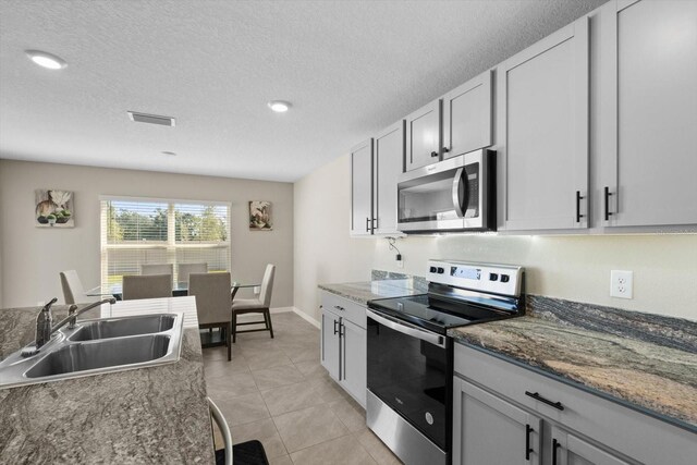 6314 Distant Haze Pl, Palmetto, FL 34221 - kitchen featuring stainless steel appliances, a sink, light tile patterned flooring, a textured ceiling, and recessed lighting