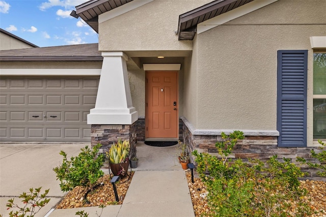 entrance to property featuring a garage, stucco siding, stone siding, and concrete driveway