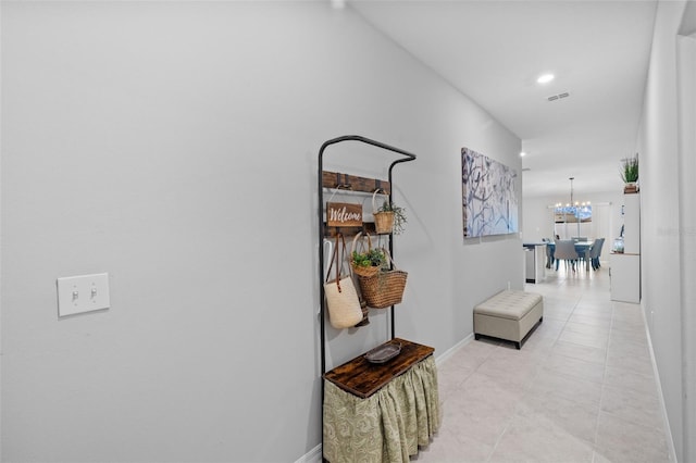 hall with baseboards, a chandelier, light tile patterned floors, and visible vents