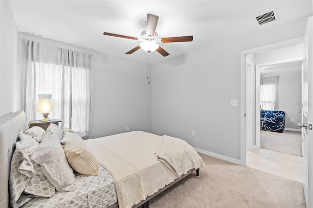 bedroom with baseboards, visible vents, light carpet, and multiple windows