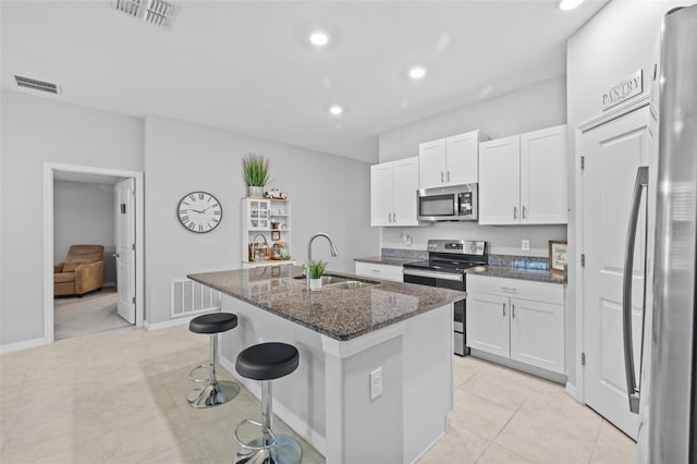 kitchen with stainless steel appliances, visible vents, a center island with sink, and a sink