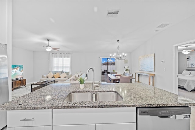 kitchen featuring ceiling fan with notable chandelier, open floor plan, white cabinetry, a sink, and appliances with stainless steel finishes