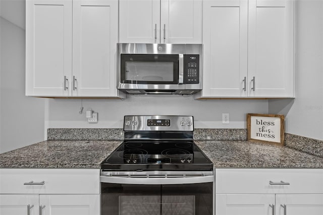 kitchen featuring white cabinets, stainless steel appliances, and dark stone countertops
