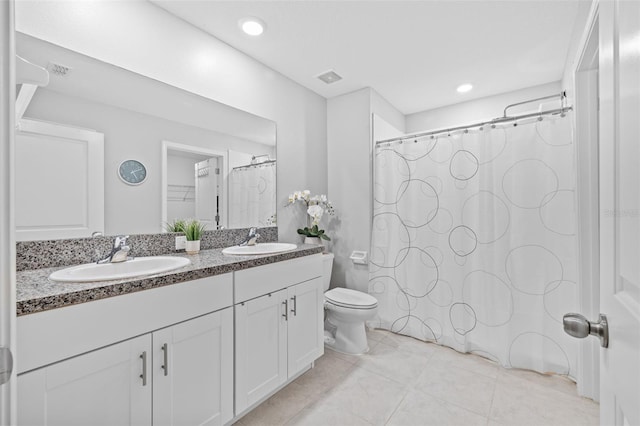 full bathroom with a sink, tile patterned floors, toilet, and double vanity
