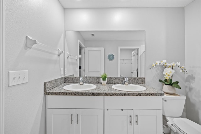 bathroom featuring a sink, toilet, and double vanity