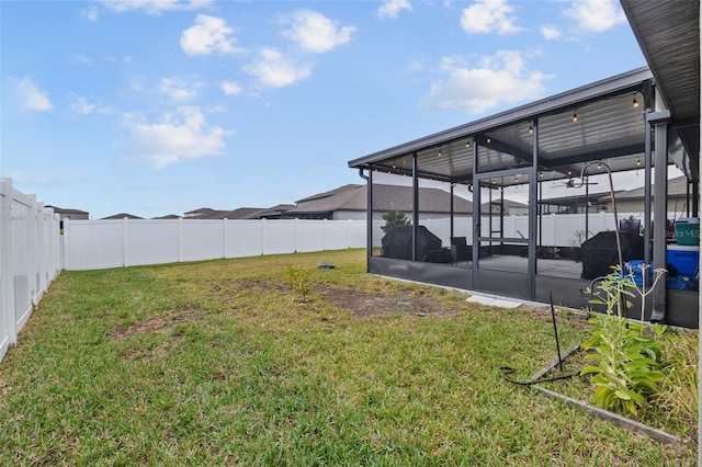 view of yard with a sunroom, a fenced backyard, and ceiling fan