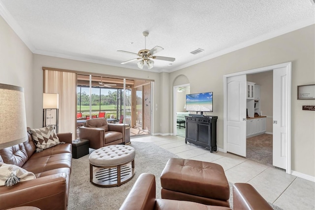 living room featuring ceiling fan, a textured ceiling, light tile patterned floors, visible vents, and ornamental molding