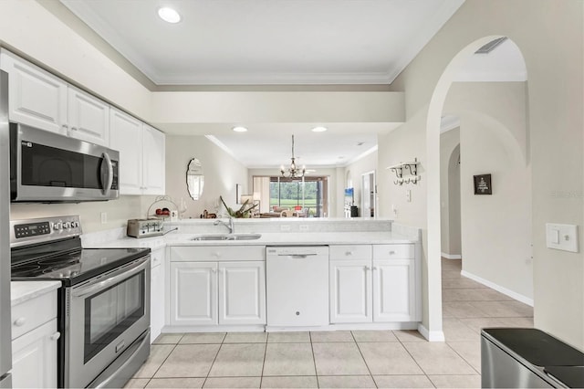 kitchen featuring arched walkways, a sink, light countertops, ornamental molding, and stainless steel appliances