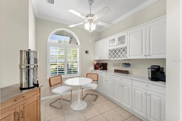 dining area with visible vents, ornamental molding, a bar, a ceiling fan, and light tile patterned floors