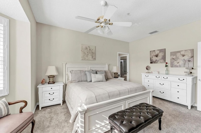 bedroom featuring light carpet, a textured ceiling, and visible vents