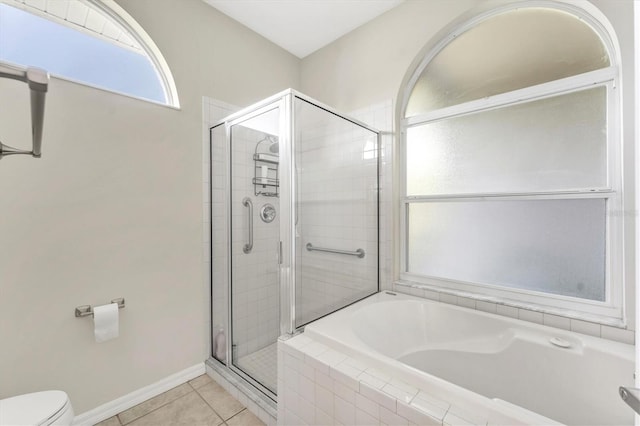 bathroom with a bath, tile patterned flooring, a shower stall, baseboards, and toilet
