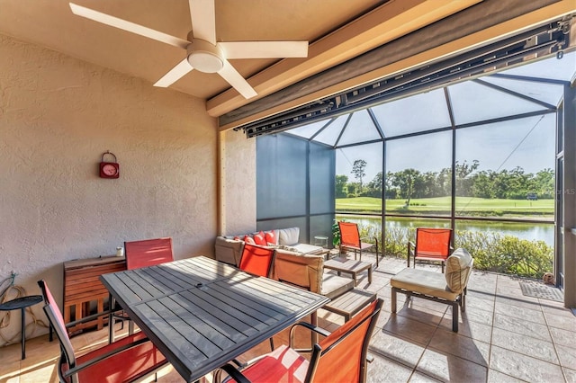 view of patio / terrace with a ceiling fan, glass enclosure, and a water view