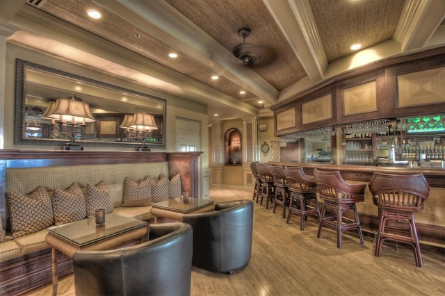 bar featuring crown molding, wood finished floors, a decorative wall, beamed ceiling, and a community bar