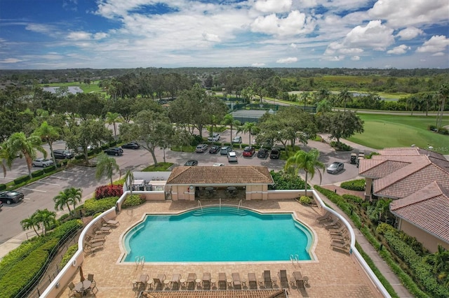community pool with view of golf course and a patio area