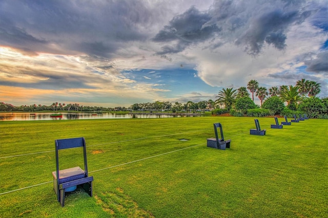 surrounding community with a water view and a yard