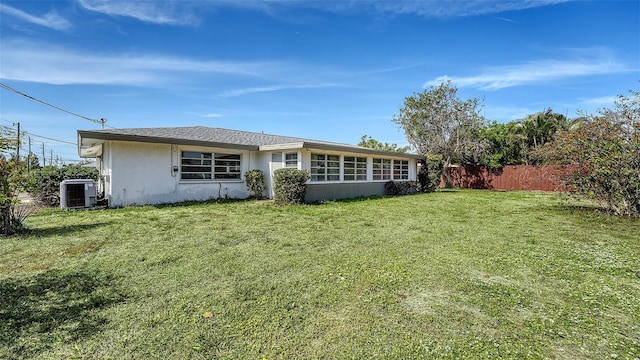 2702 Bedford Way, Sarasota, FL 34239 - rear view of property featuring a lawn, central AC unit, stucco siding, and fence