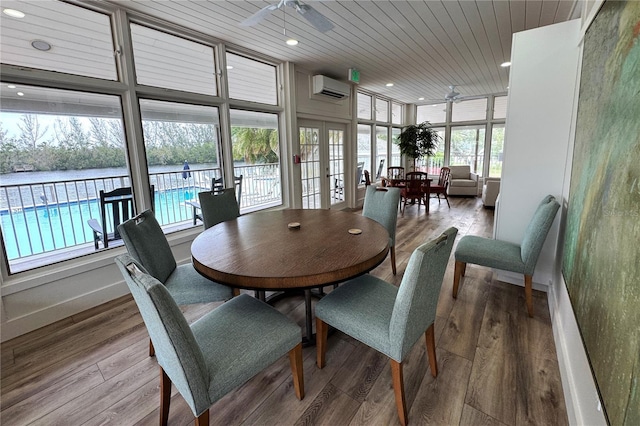 dining room with a ceiling fan, a wall mounted AC, plenty of natural light, wood ceiling, and wood finished floors