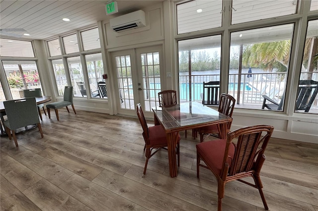 sunroom with french doors, a wall mounted air conditioner, wood finished floors, and recessed lighting