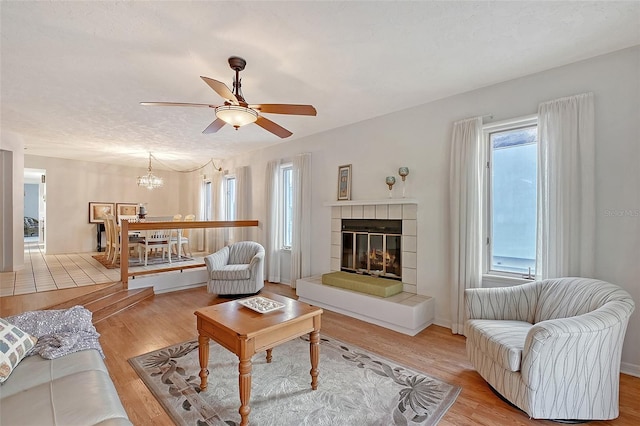 living room with plenty of natural light, wood finished floors, ceiling fan, and a chandelier