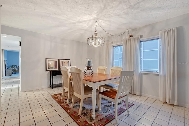 dining area featuring light tile patterned floors, a chandelier, a textured ceiling, and baseboards