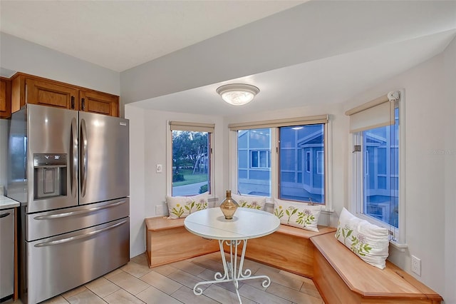 kitchen featuring stainless steel fridge, light countertops, and brown cabinetry