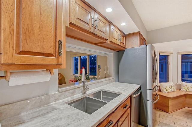 kitchen featuring a sink, light stone countertops, recessed lighting, stainless steel appliances, and brown cabinetry