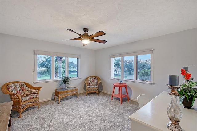 sitting room with plenty of natural light, a ceiling fan, light colored carpet, and baseboards