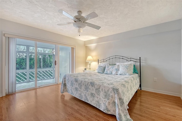 bedroom featuring access to exterior, baseboards, wood finished floors, a textured ceiling, and ceiling fan