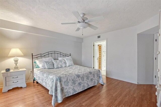 bedroom with wood finished floors, baseboards, ceiling fan, and a textured ceiling