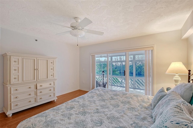 bedroom featuring access to exterior, a textured ceiling, wood finished floors, baseboards, and ceiling fan