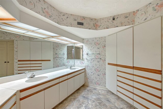 full bathroom featuring wallpapered walls and double vanity
