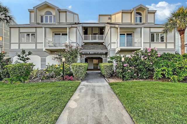 multi unit property with stucco siding and a front lawn