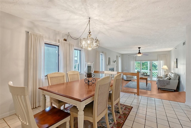 dining room featuring light tile patterned flooring, a textured ceiling, ceiling fan, a chandelier, and baseboards