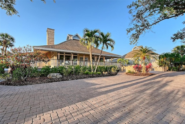 rear view of property featuring a chimney and a porch