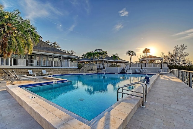 pool at dusk featuring a gazebo, a community pool, and a patio