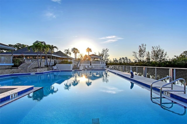 pool at dusk with a community pool and a gazebo