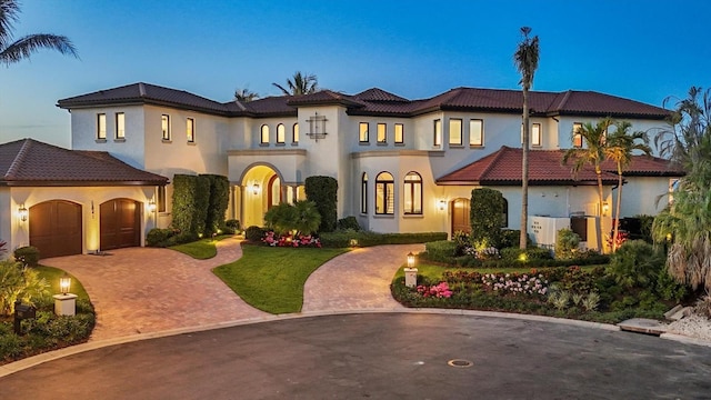 mediterranean / spanish house featuring curved driveway, stucco siding, an attached garage, and a tiled roof