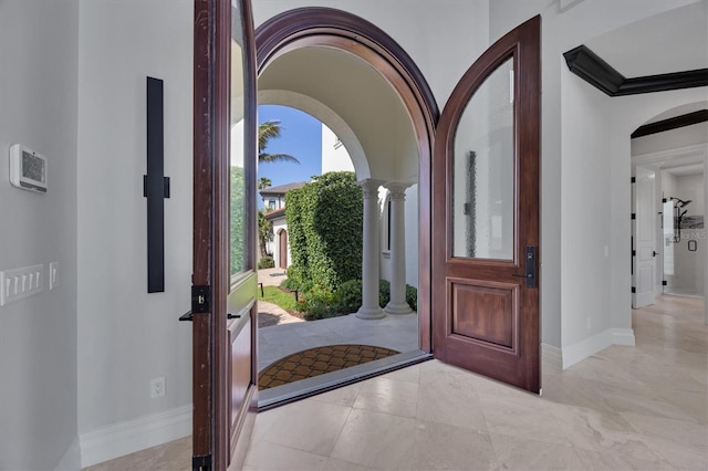 entrance foyer featuring baseboards, decorative columns, and arched walkways