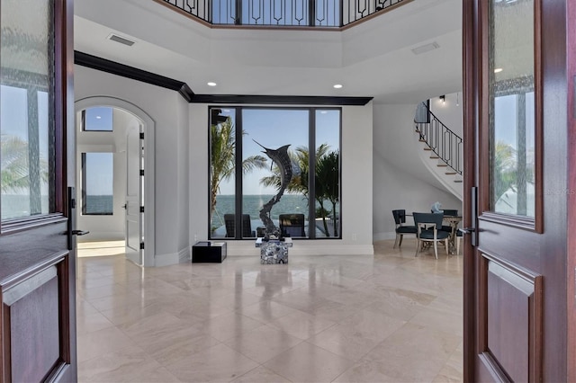 entrance foyer featuring stairs, arched walkways, baseboards, and a towering ceiling