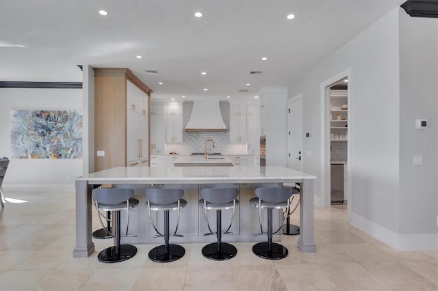 kitchen with baseboards, light countertops, tasteful backsplash, custom exhaust hood, and recessed lighting