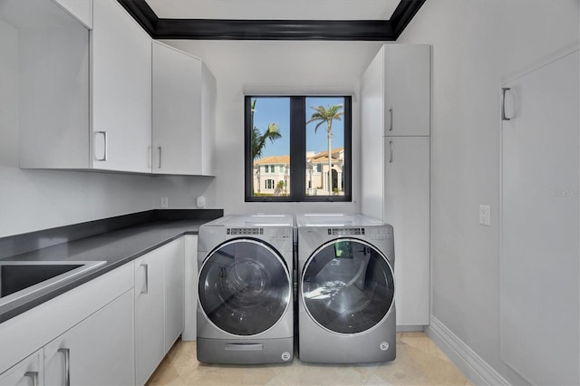 washroom with cabinet space, independent washer and dryer, baseboards, and a sink