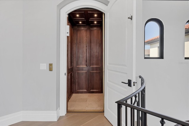 corridor featuring arched walkways, light wood-type flooring, and coffered ceiling