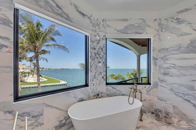 bathroom featuring a soaking tub, a wealth of natural light, and marble finish floor