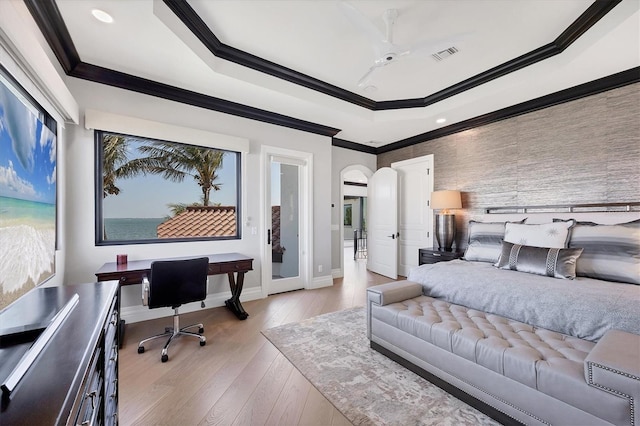 bedroom featuring ornamental molding, visible vents, light wood finished floors, a tray ceiling, and baseboards