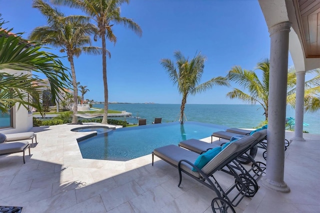 view of swimming pool with a pool with connected hot tub, a water view, and a patio